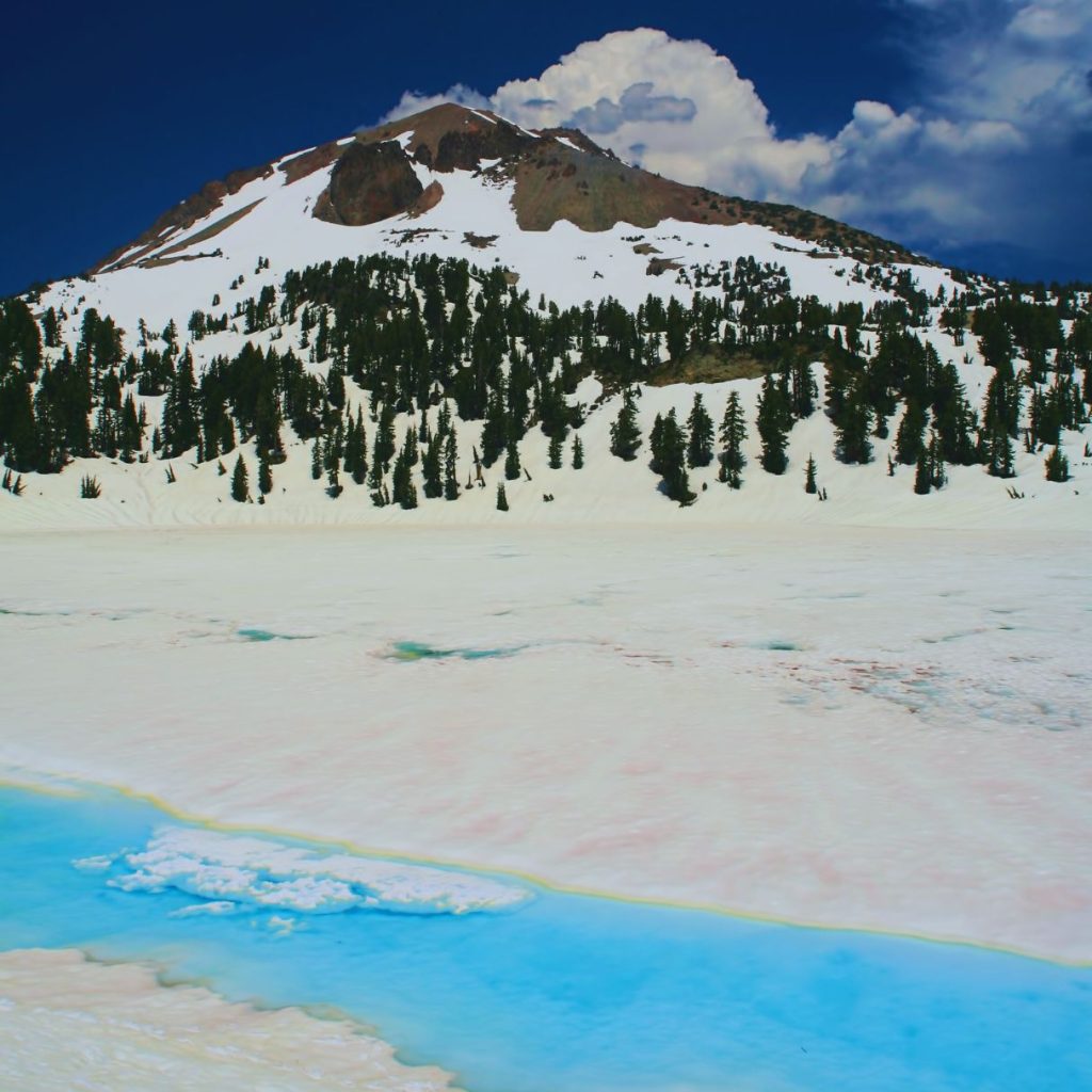 lassen volcanic national park with a snowy mountain, trees, and a blue creek